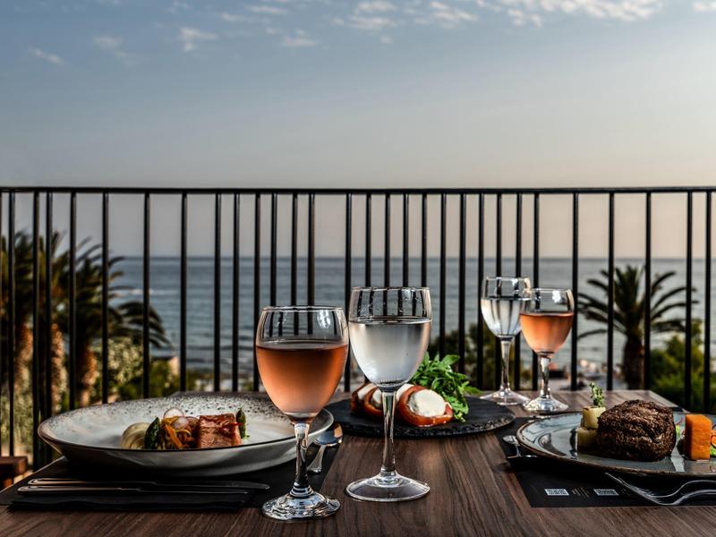 Elegante cena con vista al mar y palmeras desde la terraza balcón de un hotel.