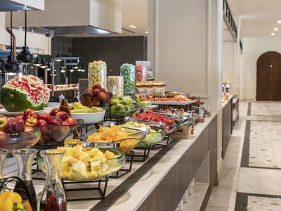 Bufé de frutas frescas y jugos en un hotel con ambiente iluminado y decorado elegantemente.