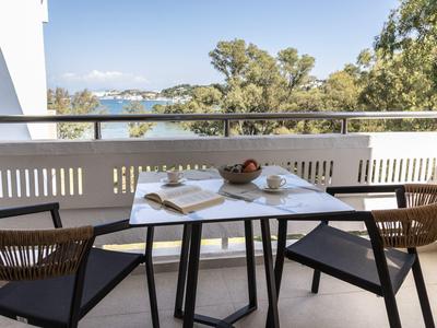 Balcone con tavolo e sedie, vista su alberi e acqua sullo sfondo