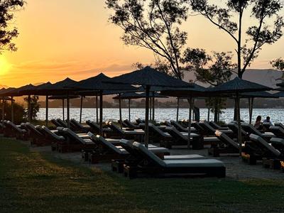 Spiaggia con lettini e ombrelloni al tramonto vicino all'acqua.
