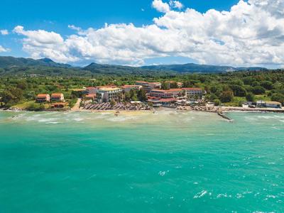 Hotelanlage am Strand mit türkisfarbenem Meer und bewölktem Himmel im Hintergrund.