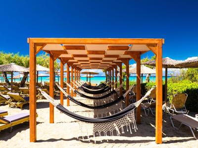 Pergola en bois avec hamacs sur une plage ensoleillée donnant sur la mer bleue