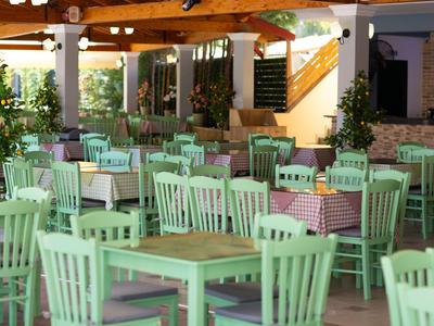 Salle à manger ouverte avec des tables et chaises en bois vert sous un toit en bois.