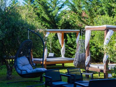 Fauteuils et chaises suspendues confortables dans un jardin verdoyant.