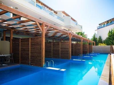 Piscina esterna moderna con tettoia in legno accanto alle camere d'hotel sotto un cielo sereno