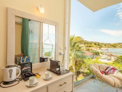 Balcone con sedia e vista sull'acqua, macchina da caffè e bollitore all'interno su comò.