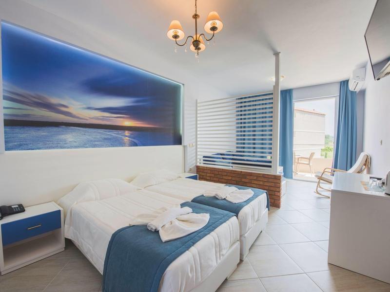 Camera d'hotel moderna con letto matrimoniale, decorazioni blu e terrazza esterna.