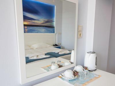White table with coffee cups, teapot, and wall mirror with landscape picture.