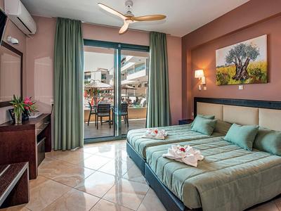 Bright hotel room with two beds, green curtains, and terrace seating area.