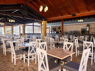 Large open dining area with wooden roof and white chairs at wooden tables.