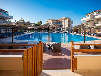 Inviting hotel pool with blue sun loungers and straw umbrellas under a clear blue sky.