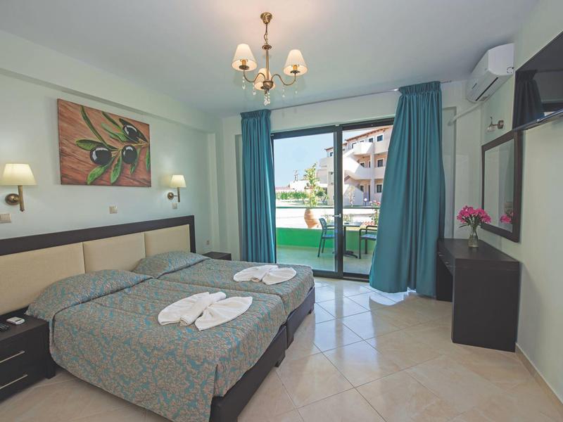 Bright hotel room with double bed, balcony, and pool view.