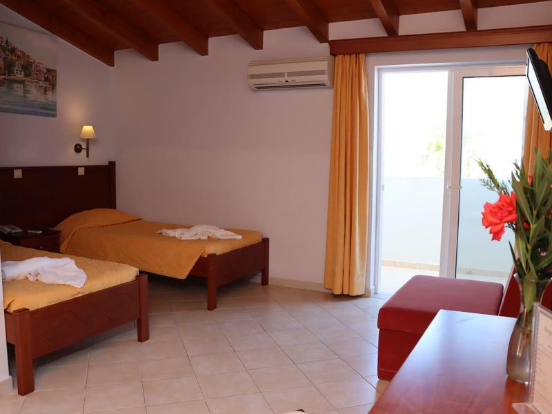 Bright hotel room with two beds, TV, and access to a balcony.