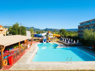 Piscina all'aperto con scivoli, ombrelloni e lettini, cielo azzurro chiaro.