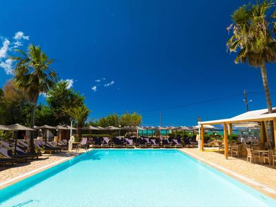 Klare blaue Poollandschaft mit Liegestühlen und Palmen unter blauem Himmel