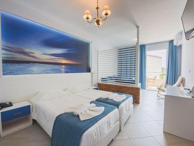 Camera d'hotel moderna con letto matrimoniale, decorazioni blu e terrazza esterna.