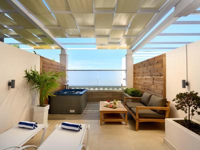 Terrazza moderna con mobili lounge e vista mare sotto un cielo limpido.