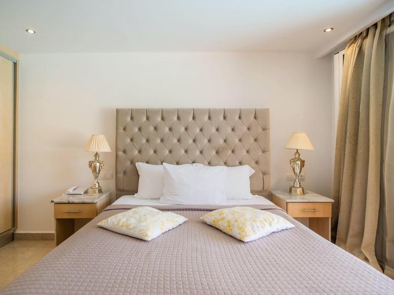 Camera d'albergo accogliente con letto matrimoniale, testiera e comodini con lampade.