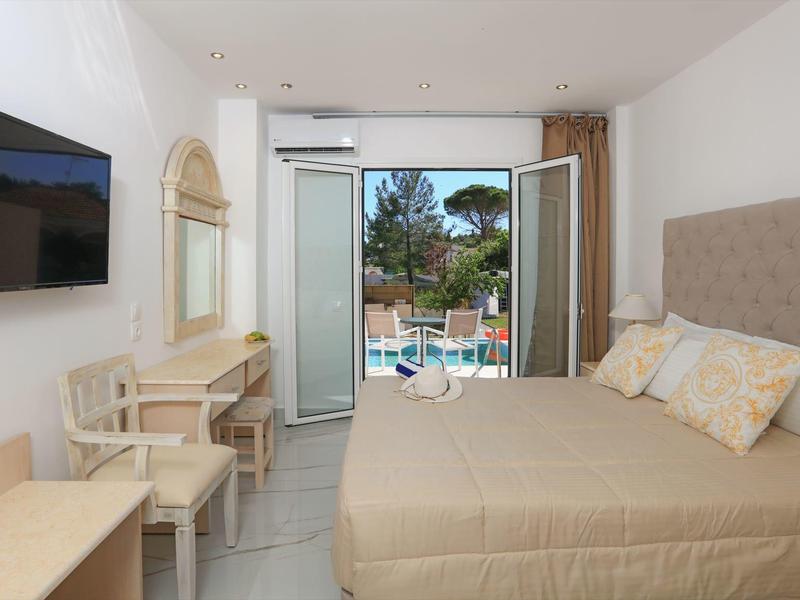 Complesso alberghiero moderno con piscina, palme e terrazza soleggiata sotto il cielo azzurro.