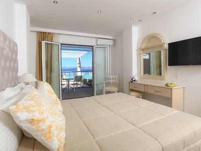 Modernes Schlafzimmer mit großem Bett, Spiegelkommode, Fernseher und Balkon mit Meerblick.