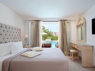 Hell eingerichtetes Hotelzimmer mit Doppelbett und Blick auf einen Pool.