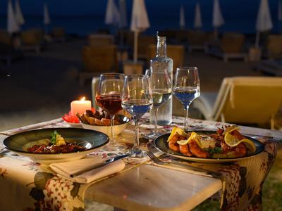 Romantisches Abendessen mit Kerzenlicht und Wein im Freien am Strand bei Nacht.