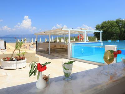 Moderne Poolbar mit Getränken, Pool und Blick auf Strand und Meer bei Sonnenschein.