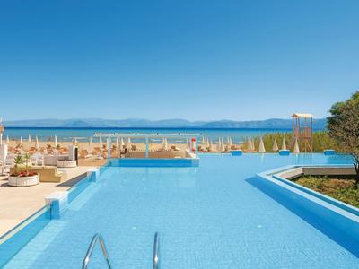 Moderner Pool mit Meerblick und Liegestühlen unter blauem Himmel