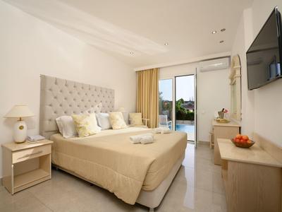 Modernes Hotelzimmer mit großem Bett, Nachttischen, Fernseher und Blick auf eine Terrasse.