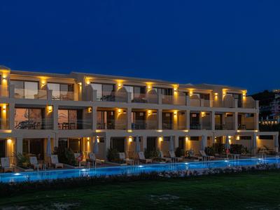 Beleuchtetes Hotelgebäude mit Terrassen und Pool bei Nacht