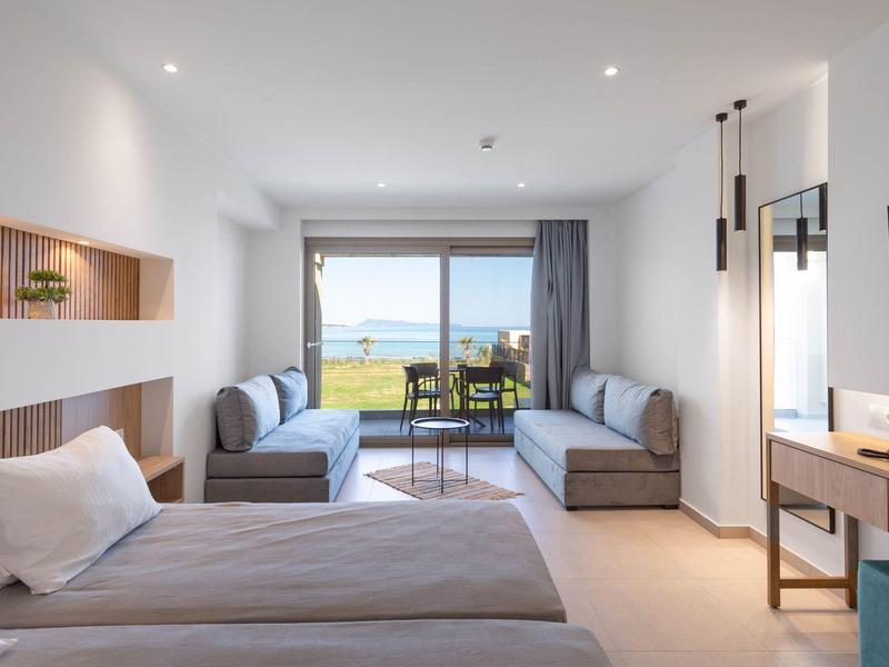 Modernes Hotelzimmer mit Doppelbett, Sitzbereich, Balkon und Meerblick in hellem, klaren Design.