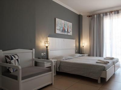 Camera d'albergo luminosa con letto matrimoniale, poltrona e grande finestra con tende.