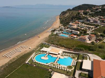 Vista di una località balneare con piscina, ombrelloni e case sulla costa.