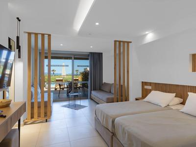 Camera d'hotel moderna con letto matrimoniale e vista su terrazza e mare.