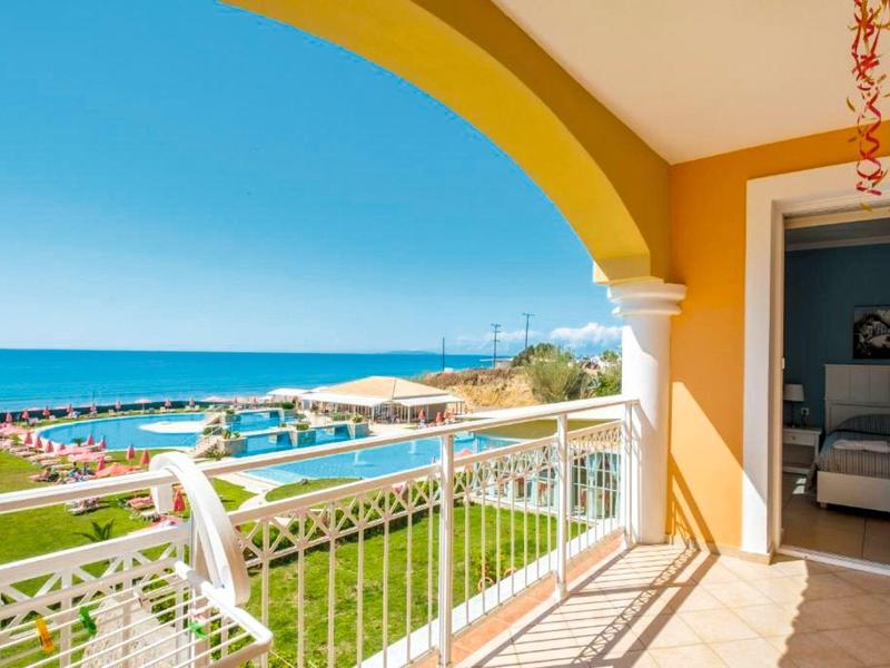 Balcone con vista mare, piscina e lettini in una giornata di sole.