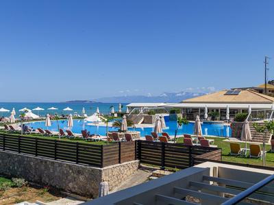 Piscina all'aperto con lettini e ombrelloni accanto al mare sotto un cielo limpido.