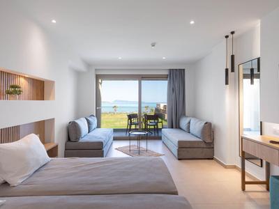 Modernes Hotelzimmer mit Doppelbett, Sitzbereich, Balkon und Meerblick in hellem, klaren Design.