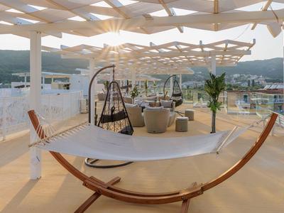 Hängematte mit Holzgestell auf sonniger Terrasse mit Pergola und Sitzgelegenheiten