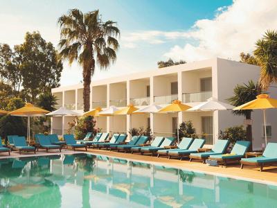 Modern hotel pool area with loungers and umbrellas under palm trees on a sunny day