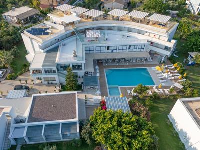 Großes, modernes Gebäude mit blauem Pool, Sonnenliegen und grünem Garten in Wohngegend.