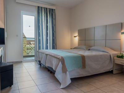 Modernes Schlafzimmer mit Doppelbett, grauer Bettdecke, blauem Vorhang und Balkonzugang.