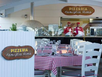 Gemütliche Pizzeria mit rot-weiß karierten Tischtüchern, Holztischen und wartendem Personal.