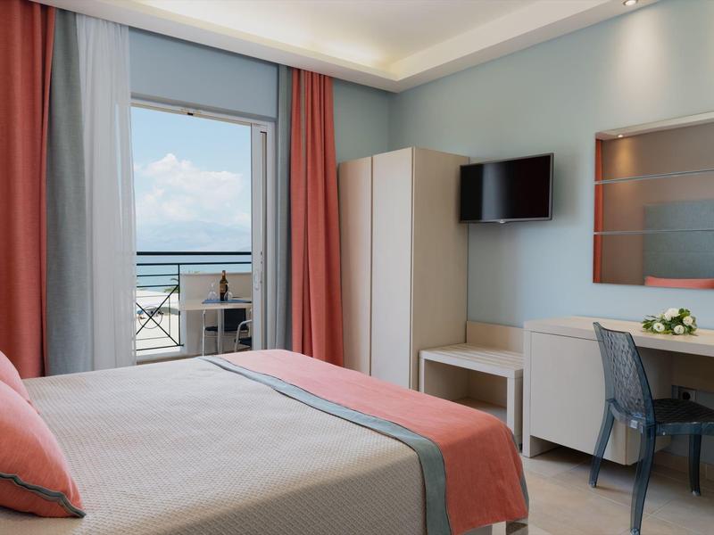 Helles Schlafzimmer mit Doppelbett, Terrassentür, TV, weißem Schrank und Schreibtisch mit Stuhl.