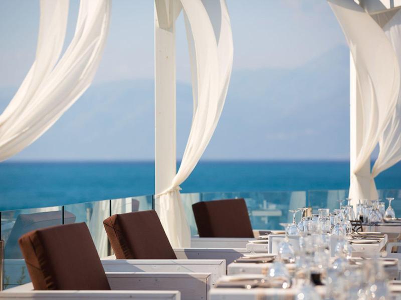Eleganter Außenbereich mit gedeckten Tischen und Meerblick an einem sonnigen Tag.