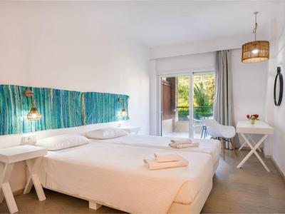 Helles Schlafzimmer mit zwei Einzelbetten, weißen Möbeln und Balkon mit Blick ins Grüne.