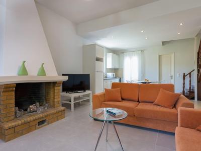 Soggiorno luminoso con camino, divano arancione e TV in un appartamento moderno per vacanze.