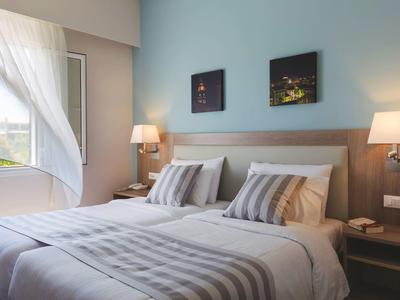 Camera d'hotel accogliente con letto matrimoniale, biancheria a righe e comodini illuminati.