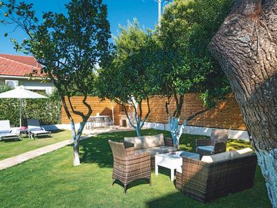 Giardino con prato, mobili da giardino e alberi vicino a un edificio.