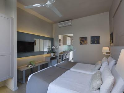 Camera d'hotel moderna con due letti singoli, scrivania e aria condizionata.