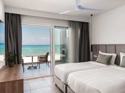 Camera d'hotel moderna con letto matrimoniale e vista mare attraverso grandi porte scorrevoli in vetro.